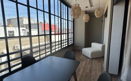 Terrasse aménagée avec baie vitrée et table à manger, studio lumineux au dernier étage au Maarif