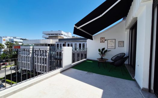Terrasse de 15m² aménagée avec store banne noir, salon de jardin, gazon synthétique et vue dégagée sur le quartier Gauthier, appartement 4ème étage résidence neuve Casablanca